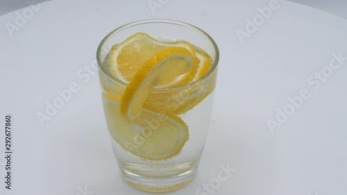 Lemon juice in glass rotation on white background, healthy served drink in the morning. photo