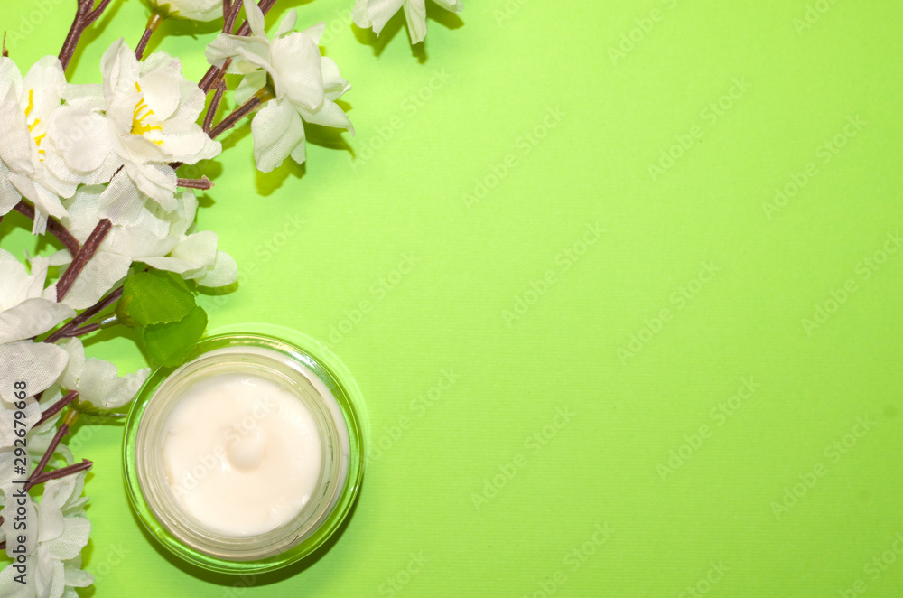 Beautiful composition with cosmetics on light green background, flat lay with skin cream and wthite flowers, spring background with a copy space for an your text, clean beauty concept, top view Beautiful composition with cosmetics on light green background, flat lay with skin cream and wthite flowers, spring background with a copy space for an your text, clean beauty concept, top view