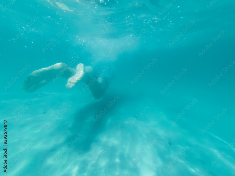 Young man is swimming in the blue deep sea. Underwater shoot