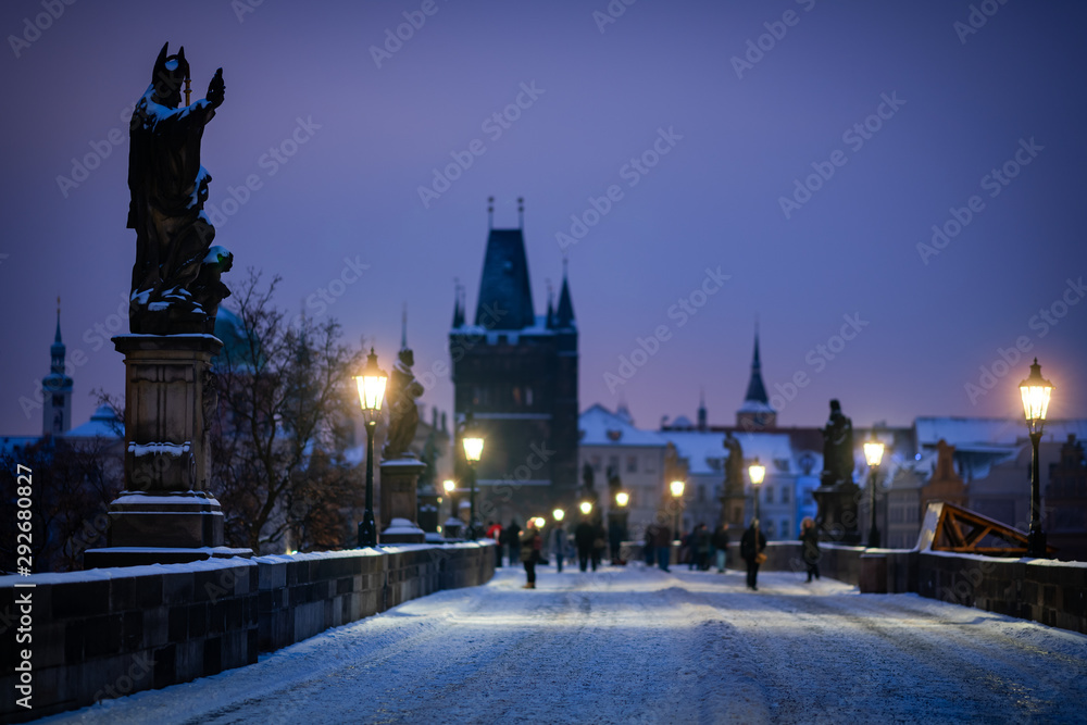 Obraz premium The statue of Augustine of Hippo on the Charles Bridge in Prague. Winter scene with snow on the bridge.