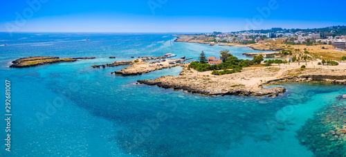 Fototapeta Naklejka Na Ścianę i Meble -  Panorama of Cyprus on a Sunny day. The mediterranean coast. The Port Of Pernera. There's a yacht in the Harbor. The house with a brown roof is located on a picturesque Cape. Rest, vacation, relaxation
