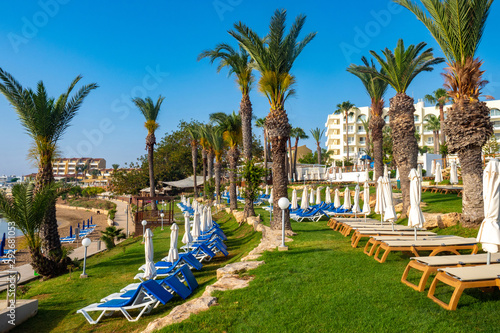 Island of Cyprus. Kalamies beach is empty. Pernera. Sun loungers and parasols are arranged in neat rows. Palm trees. Cyprus beach resort. Hotels with beaches near the Mediterranean sea. photo