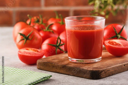 Tasty Tomato juice in a glass with ripe red tomatoes.