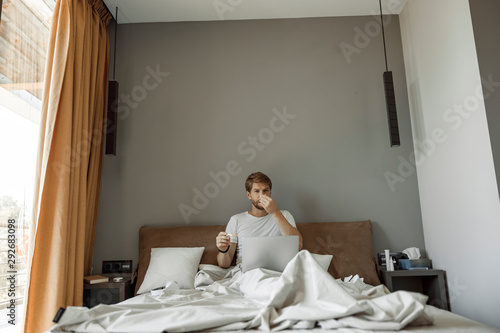 Man being affected by cold sitting in his bed