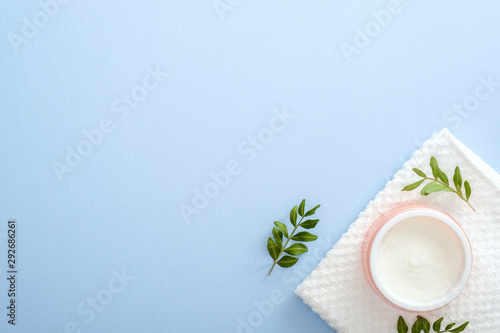 Moisturizing care skincare face cream for healing complicated troubled skin type in an open jar and towel decorated eucalyptus leaves. Flat lay, top view, overhead. Skin care and healthcare concept.