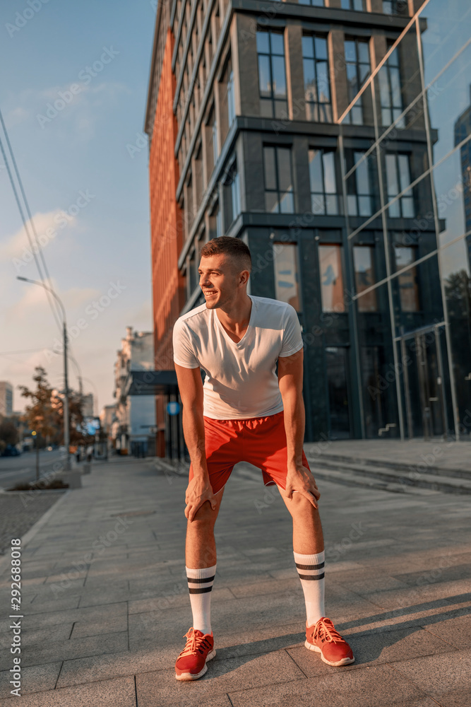 Joyous sportive cute young man training outside Joyous sportive cute young man training outside