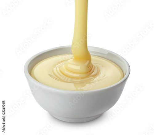 Pouring condensed milk isolated on white background photo