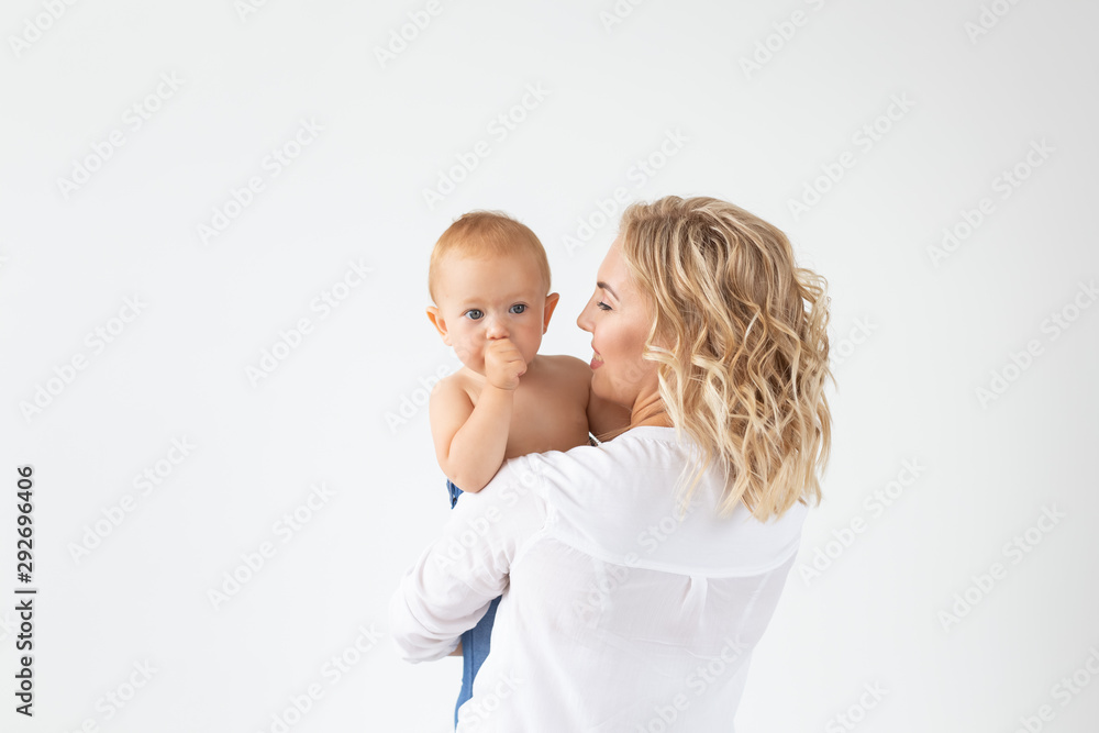 Childhood, motherhood and family concept - Portrait happy mother holds her baby on white background with copy space Childhood, motherhood and family concept - Portrait happy mother holds her baby on white background with copy space