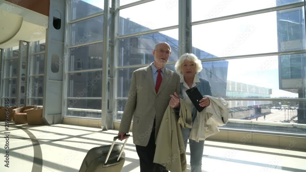 Senior couple in airport walking with suitcase. Holiday travel background. Senior couple in airport walking with suitcase. Holiday travel background.