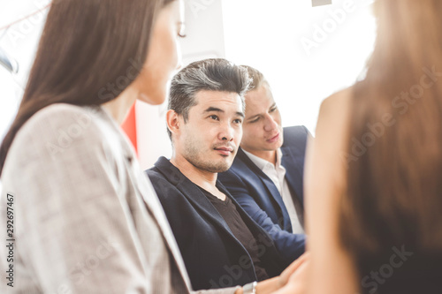 A team of young office workers, businessmen with laptop working at the table, communicating together in an office. Portrait of a successful man