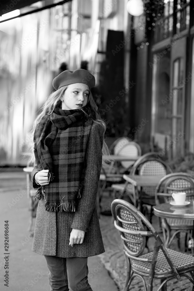 young girl in a red beret and a gray coat near a cafe