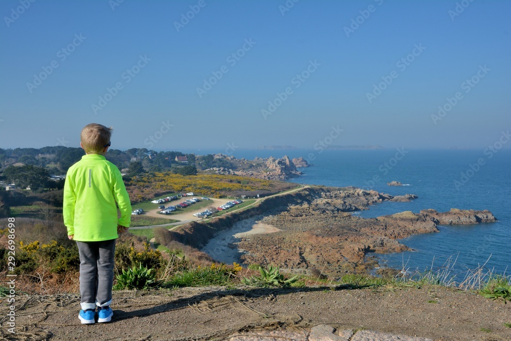 Petit garçon qui regarde la mer sur la côte de granit rose en Bretagne. France Petit garçon qui regarde la mer sur la côte de granit rose en Bretagne. France