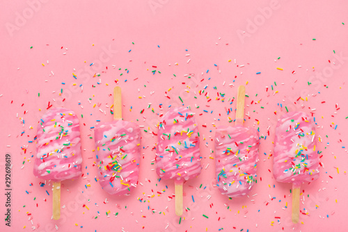 фотографія popsicle with sprinkles and icing on pink festive background with copy space