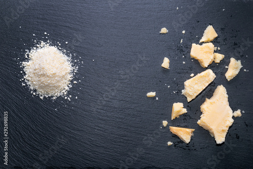 top view of tasty fresh pieces cheese and grated parmigiano on black slate background