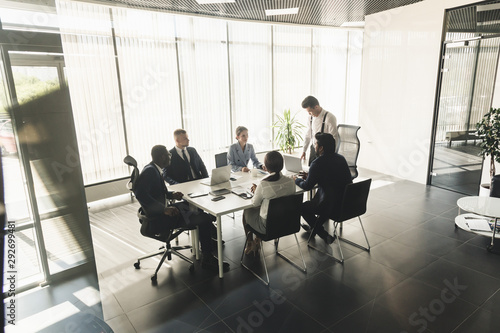 Silhouettes of people sitting at the table. A team of young businessmen working and communicating together in an office. Corporate businessteam and manager in a meeting