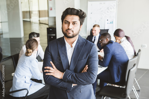 Business man stands on the background of partners. A team of young businessmen working and communicating together in an office. Corporate businessteam and manager in a meeting.