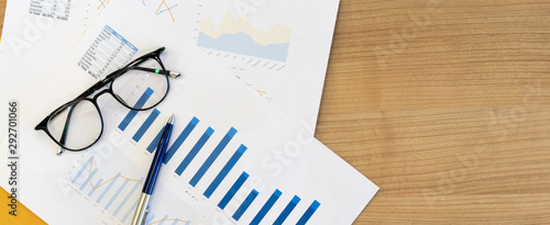 close up top view of statistic graph and chart summary report paperwork with pen and glasses on wood table to show the company profit in the meeting event at conference room,business financial concept photo