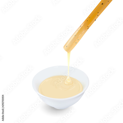 Bread stick dipped with condensed milk in cup on white background.