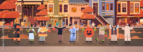 people wearing different monsters costumes walking in town tricks and treat happy halloween party celebration concept city street buildings cityscape background full length horizontal