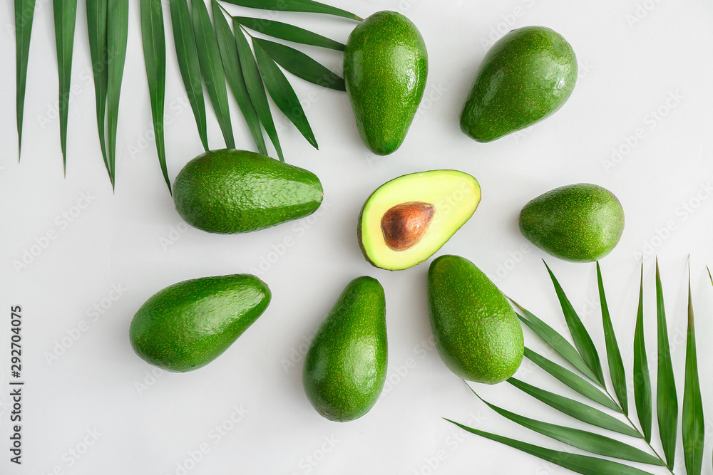 Fresh ripe avocados and palm leaves on white background Fresh ripe avocados and palm leaves on white background