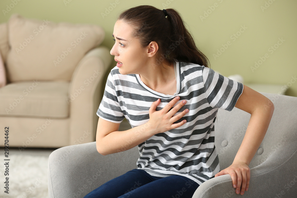 Obraz premium Young woman suffering from heart attack at home