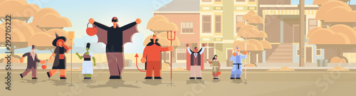 people wearing different monsters costumes walking in town tricks and treat happy halloween party celebration concept city street buildings cityscape background full length horizontal
