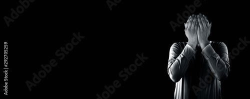 Valokuva Embarrassed business employee worker wearing a corporate blue shirt with black necktie isolated on black background covering his face with his hands