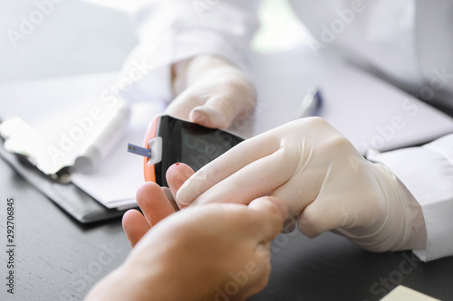 Doctor checking blood sugar level of diabetic patient in clinic, closeup