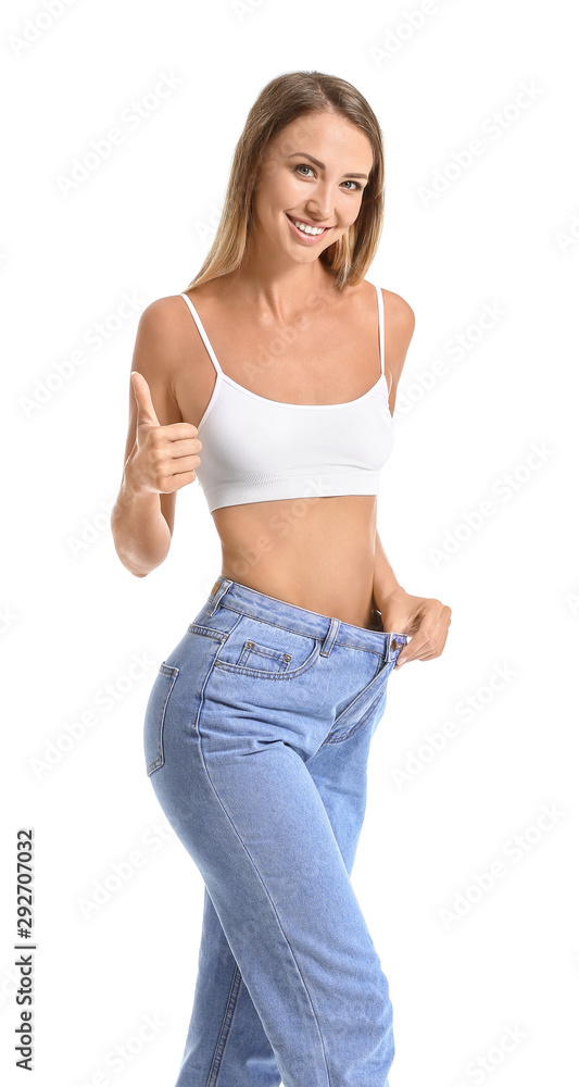 Beautiful young woman in loose jeans showing thumb-up on white background. Weight loss concept Beautiful young woman in loose jeans showing thumb-up on white background. Weight loss concept