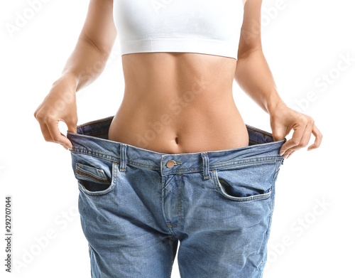 Beautiful young woman in loose jeans on white background. Weight loss concept © Pixel-Shot