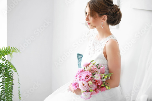 Beautiful young bride with bouquet before wedding ceremony at home