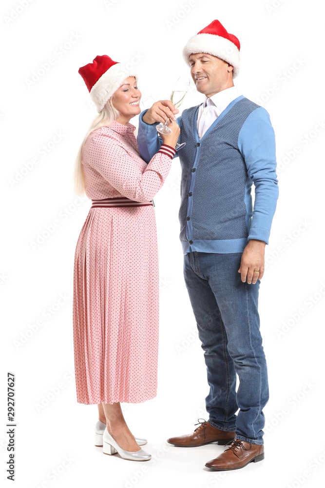 Obraz premium Portrait of happy mature couple in Santa Claus hats and with glasses of champagne on white background