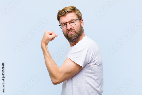 Quadro su tela young blonde adult man feeling happy, satisfied and powerful, flexing fit and mu