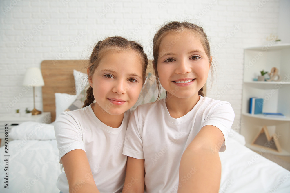 Portrait of twin girls taking selfie in bedroom Portrait of twin girls taking selfie in bedroom