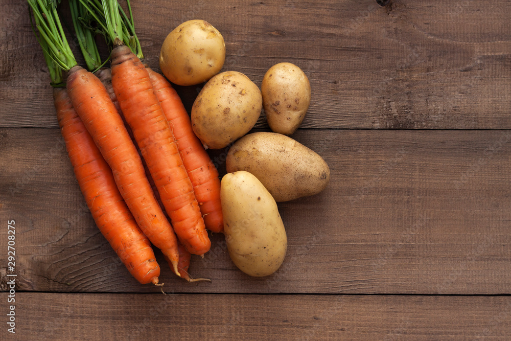 Fresh carrots and potatoes on a wooden background. Harvest season Fresh carrots and potatoes on a wooden background. Harvest season