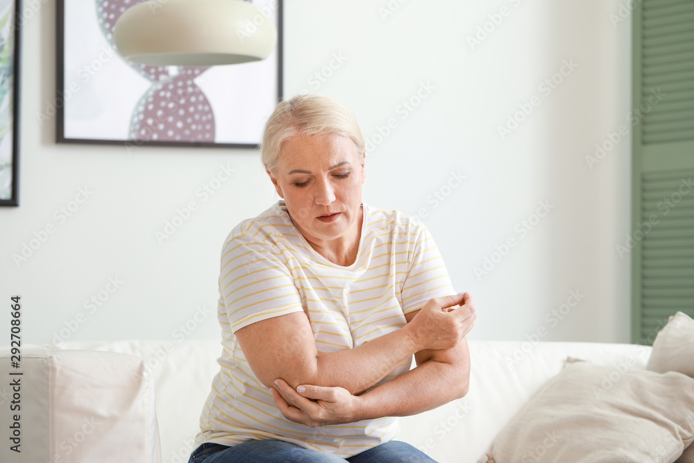 Mature woman suffering from pain in elbow at home Mature woman suffering from pain in elbow at home