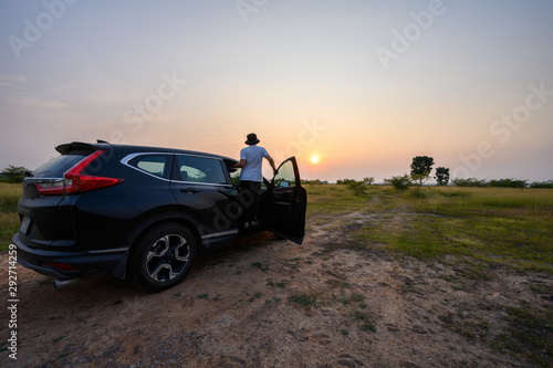 Travel concept  Female tourist standing watching sunset on the car
