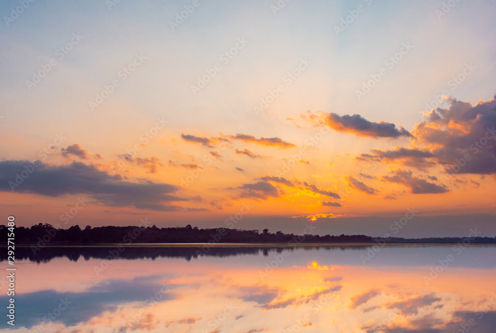Sunset reflection lagoon. beautiful sunset behind the clouds and blue sky above the over lagoon landscape background. dramatic sky with cloud at sunset.