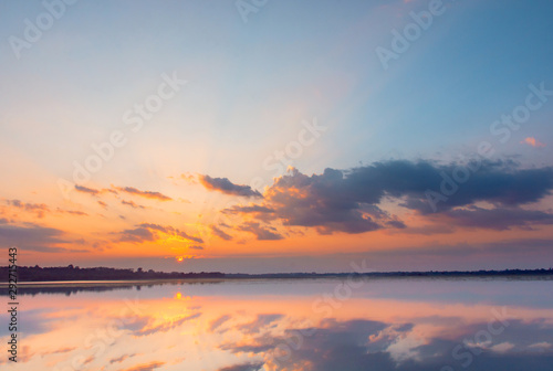 Sunset reflection lagoon. beautiful sunset behind the clouds and blue sky above the over lagoon landscape background. dramatic sky with cloud at sunset. © Achira22