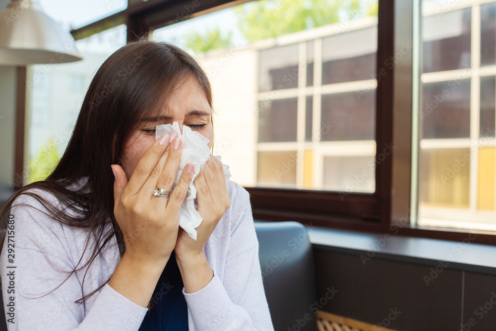 Brunette woman blowing nose into tissue Brunette woman blowing nose into tissue