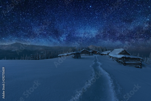 Fairytale landscapes of the winter Carpathian Mountains with a charming milky way in the sky tourist tents and snowy houses in the valleys © reme80