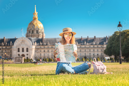 Asian happy girl traveler lying on a grass and reading map near the Invalides In Paris. Lifestyle and tourism in France © EdNurg