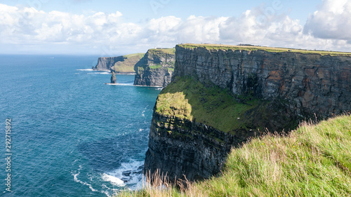 Beautiful view of the famous Cliffs of Moher in County Clare, Ireland. Showing the green grass, blue sky & blue waters of the Atlantic.