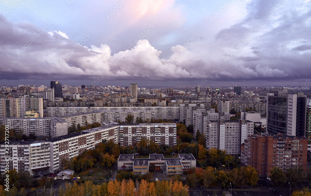 aerial cityscape. evening over the capital of Siberia - Novosibirsk. heavy dark clouds over the city and fall foliage on trees among urban high-rise buildings