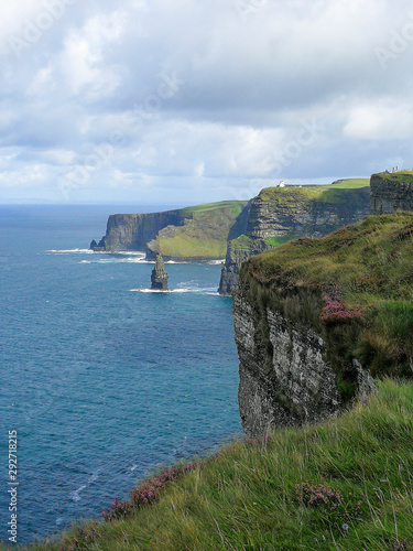 View of the famous Cliffs of Moher in County Clare, Ireland. Taken on a sunny summer day showing the deep blue water of the Atlantic ocean & blue sky with clouds.
