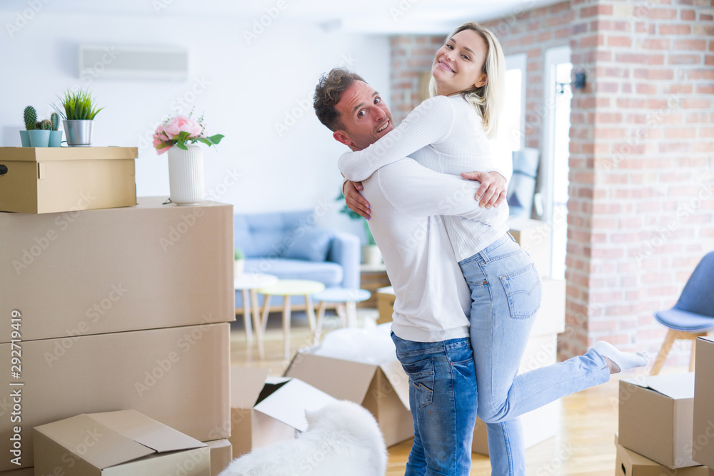 Young beautiful couple with dog hugging at new home around cardboard boxes Young beautiful couple with dog hugging at new home around cardboard boxes