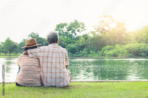 Cuadro en lienzo An elderly couple hugging each other with love and happiness in a park with a large pond