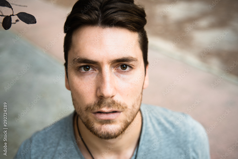 Fototapeta premium Handsome male model in gray shirt looking at camera with calm pose.