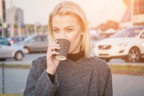 Head shot portrait of stylish young woman drinking coffee at city street