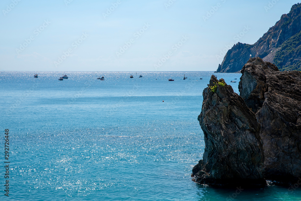Rocks in sea with boats on background